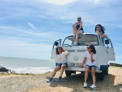Quatre filles posant avec un fourgon sur la plage